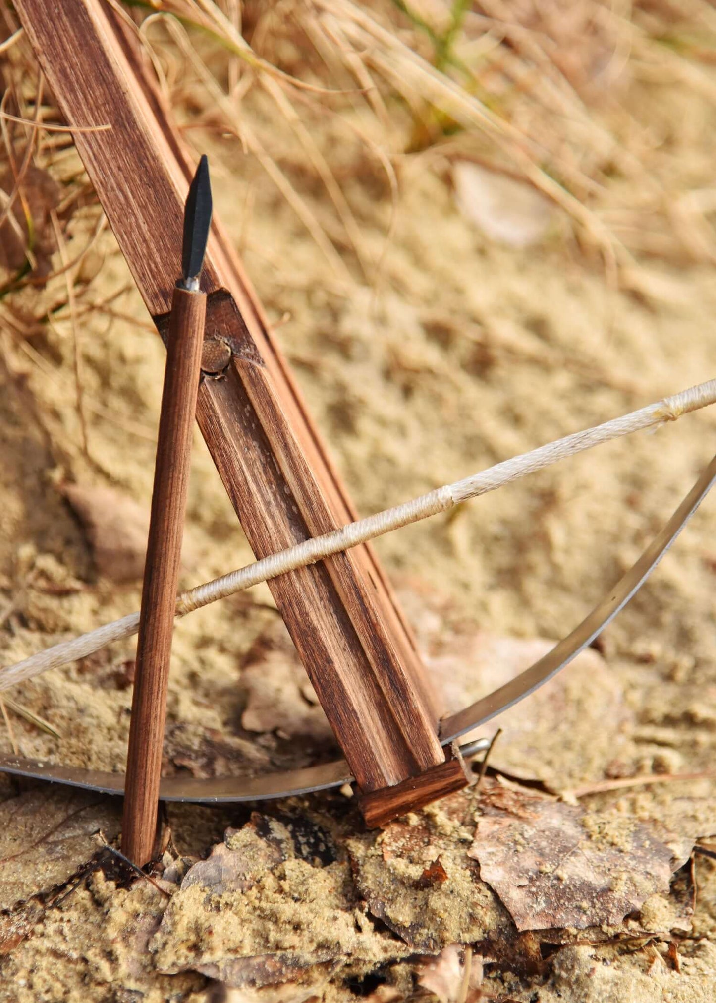 Miniatur armbrust auf dem Boden, gefertigt aus Holz und mit einem Pfeil, ideal für Sammler und historische Reenactments.