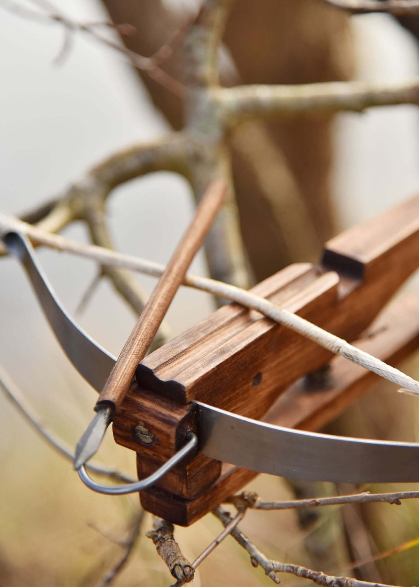 Miniatur Armbrust aus Holz mit einem Bolzen, platziert auf einem Ast in der Natur.