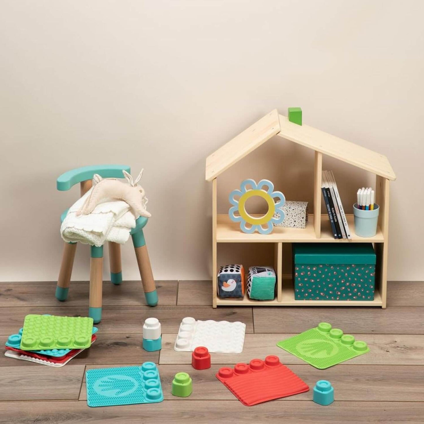 Colorful sensory play area featuring a wooden playhouse, cute toys, and sensory tiles for children.
