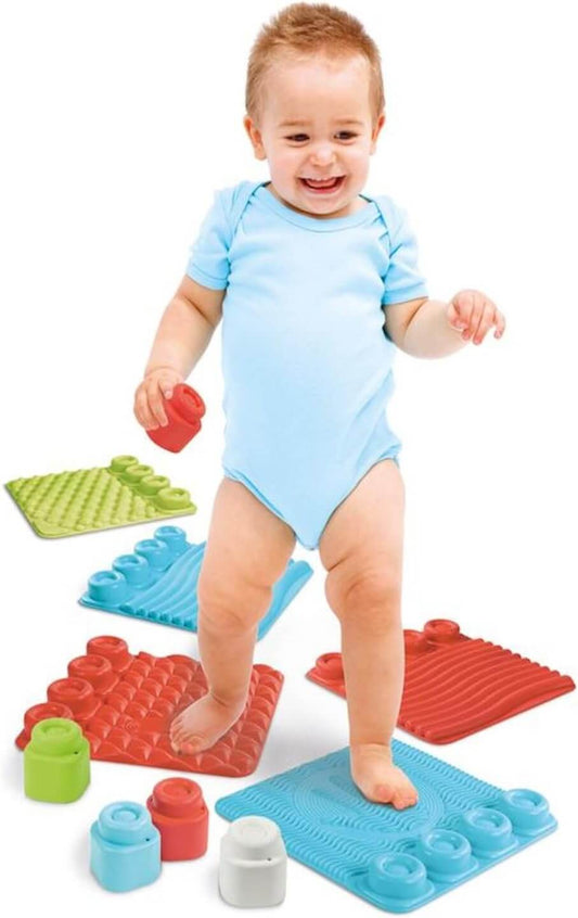 Happy toddler playing on colorful sensory play mat with building blocks, promoting motor skills and tactile perception.